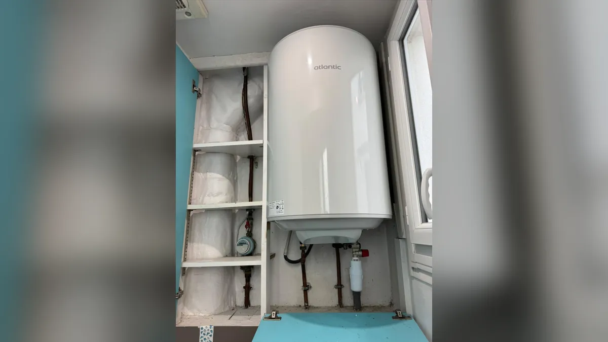 Chauffe-eau Atlantic mural dans un placard de cuisine, à côté du compteur d’eau