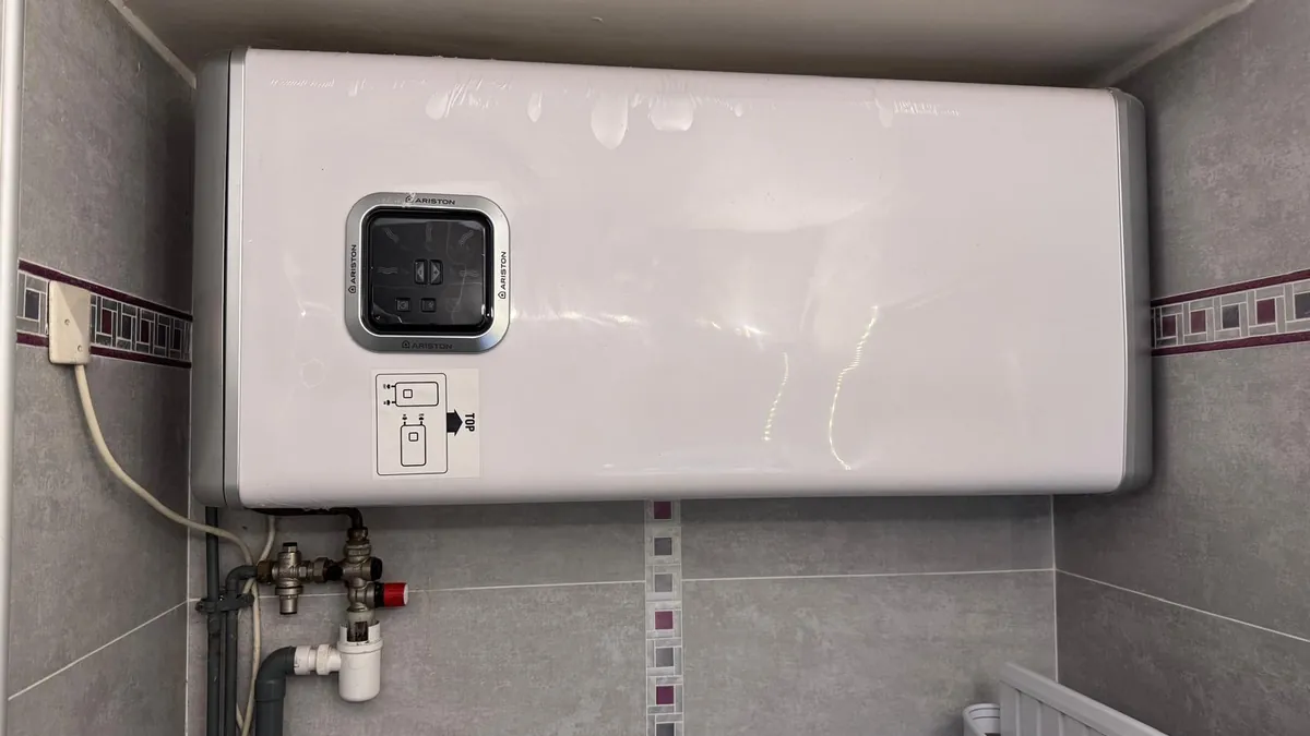 Chauffe-eau plat Ariston posé à l’horizontale dans une niche carrelée de salle de bains