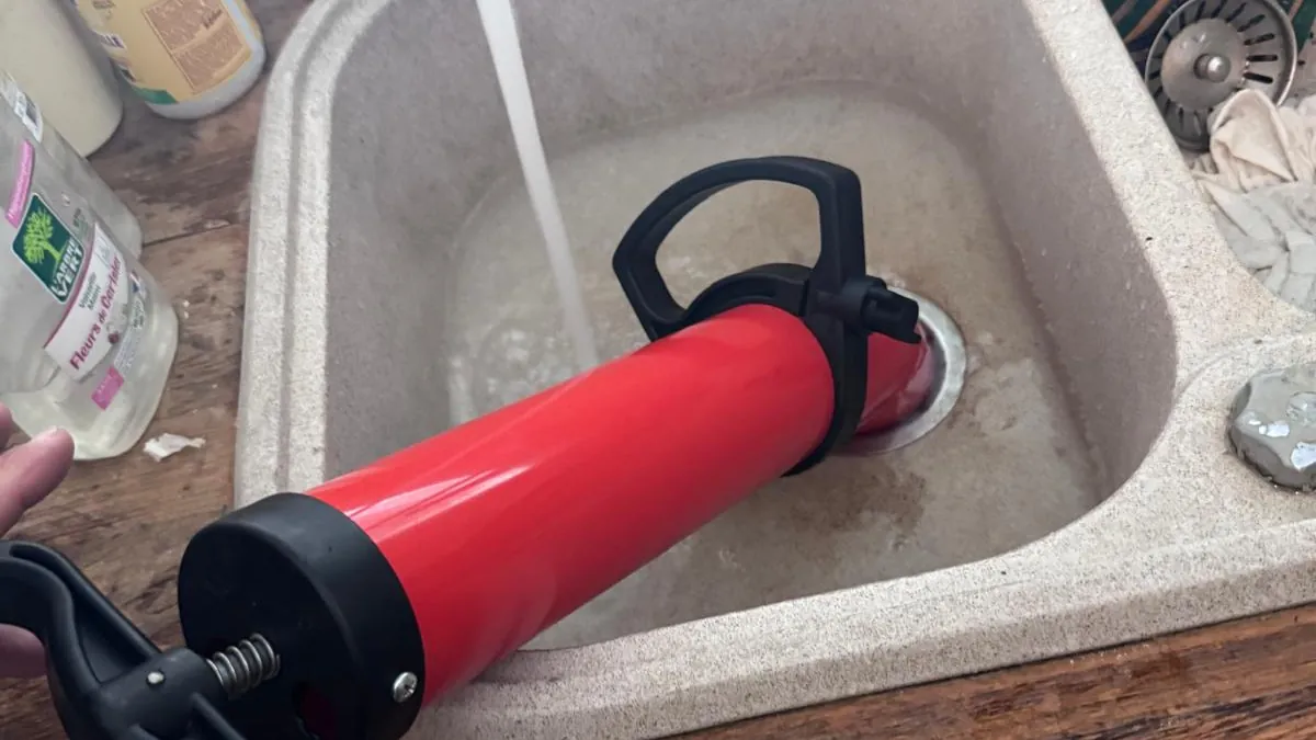Pompe à déboucher appliquée sur la bonde d’un évier en résine rempli d’eau