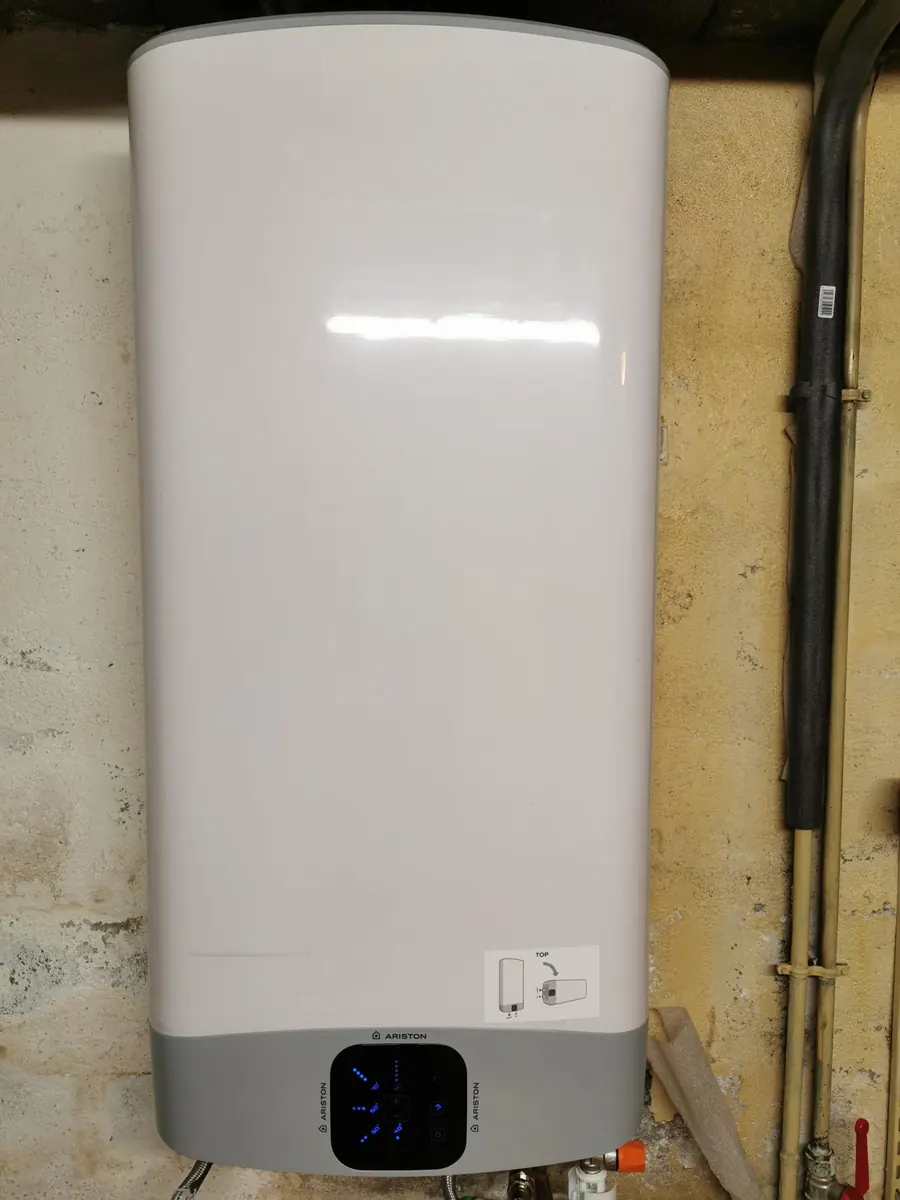 Chauffe-eau plat Ariston fixé au mur d’une cave, écran de commande allumé