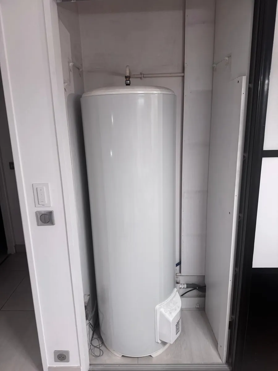 Chauffe-eau vertical sur socle installé dans un placard à porte coulissante