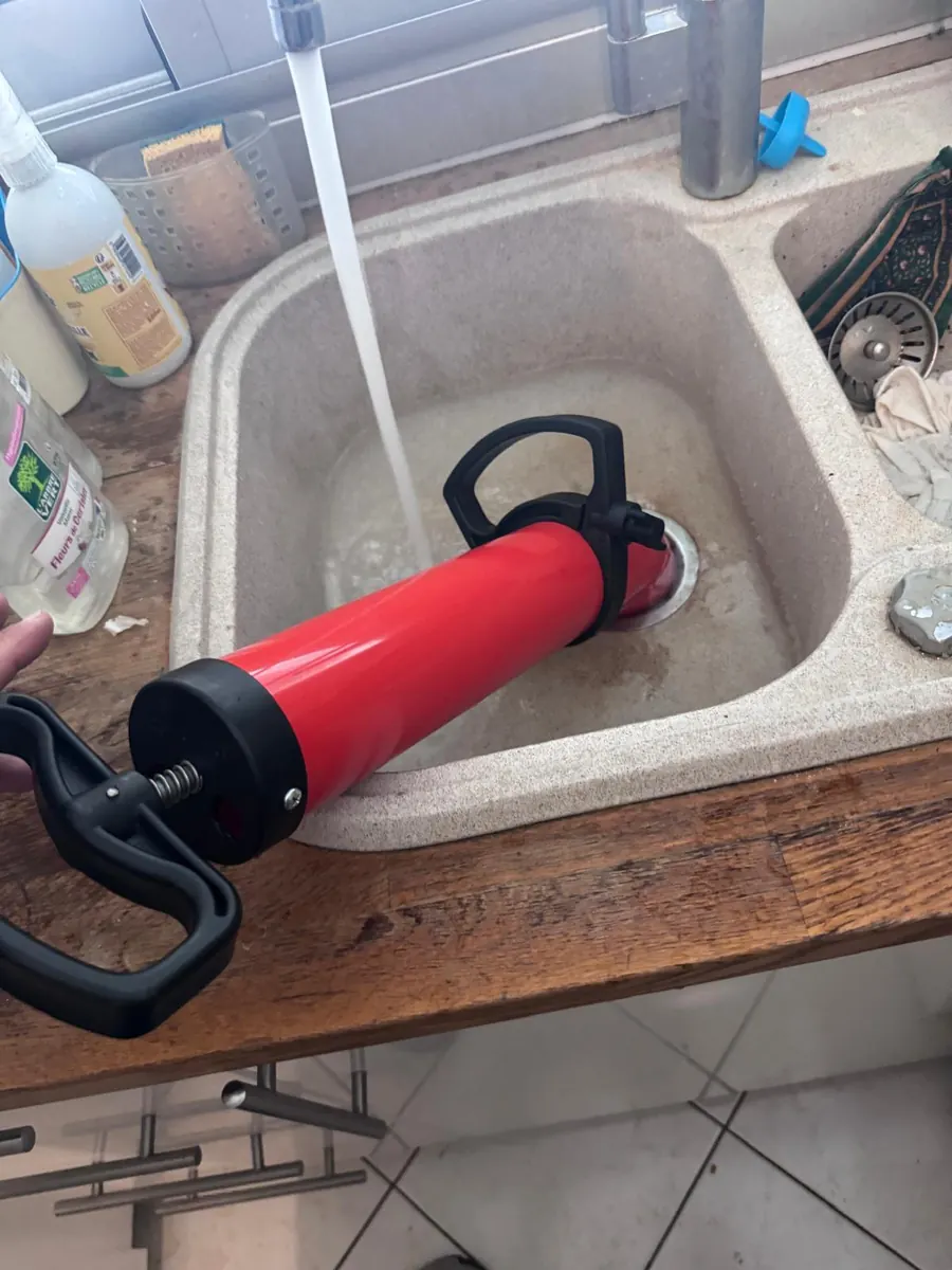 Pompe à déboucher rouge appliquée sur la bonde d’un évier en résine rempli d’eau